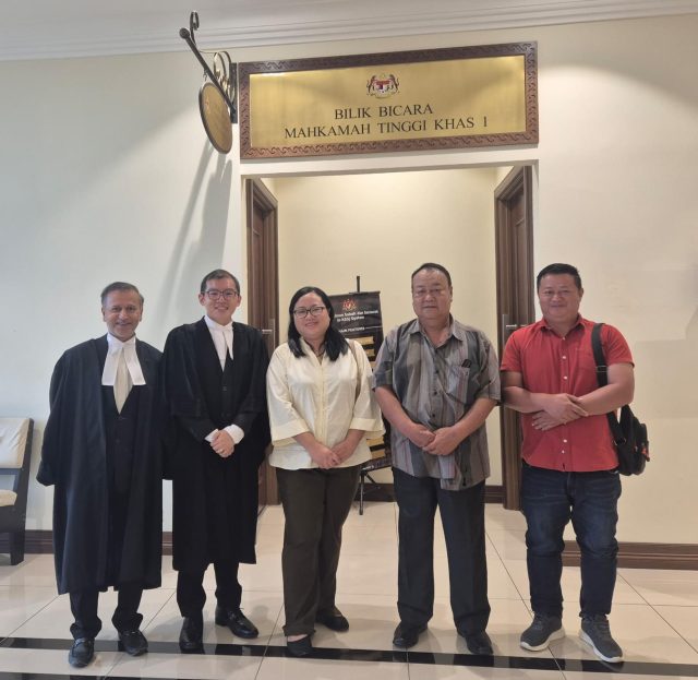Abdul Manap bin Bakusai (2nd from right) and two of his children pose for a photograph with our Hassan Murtaza (left) and Adam Chin (2nd from left) after a hearing in open court.